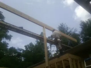 Carpenter setting a ridge beam over a new addition frame — Ice Dam Removal by Roofing Brothers in Poneto
