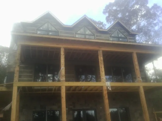 Dormers and porch framing on a large log home under construction — Roof Coating work by our crew in Poneto