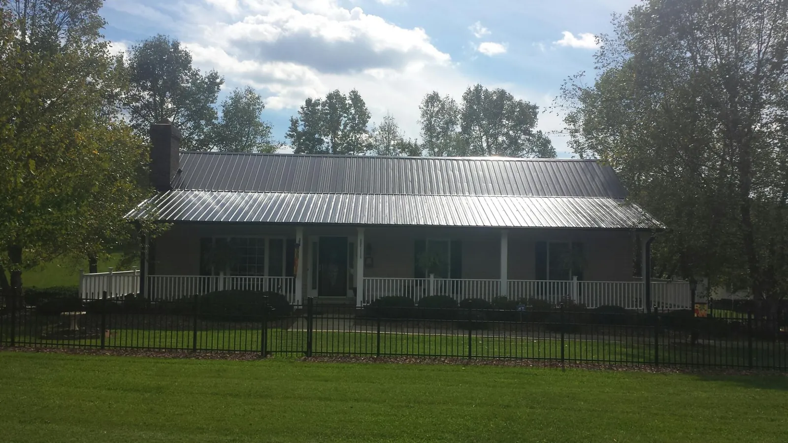 Gray metal roof on a brick ranch with a full width front porch — Gutter Guard Installation work by our crew in Poneto