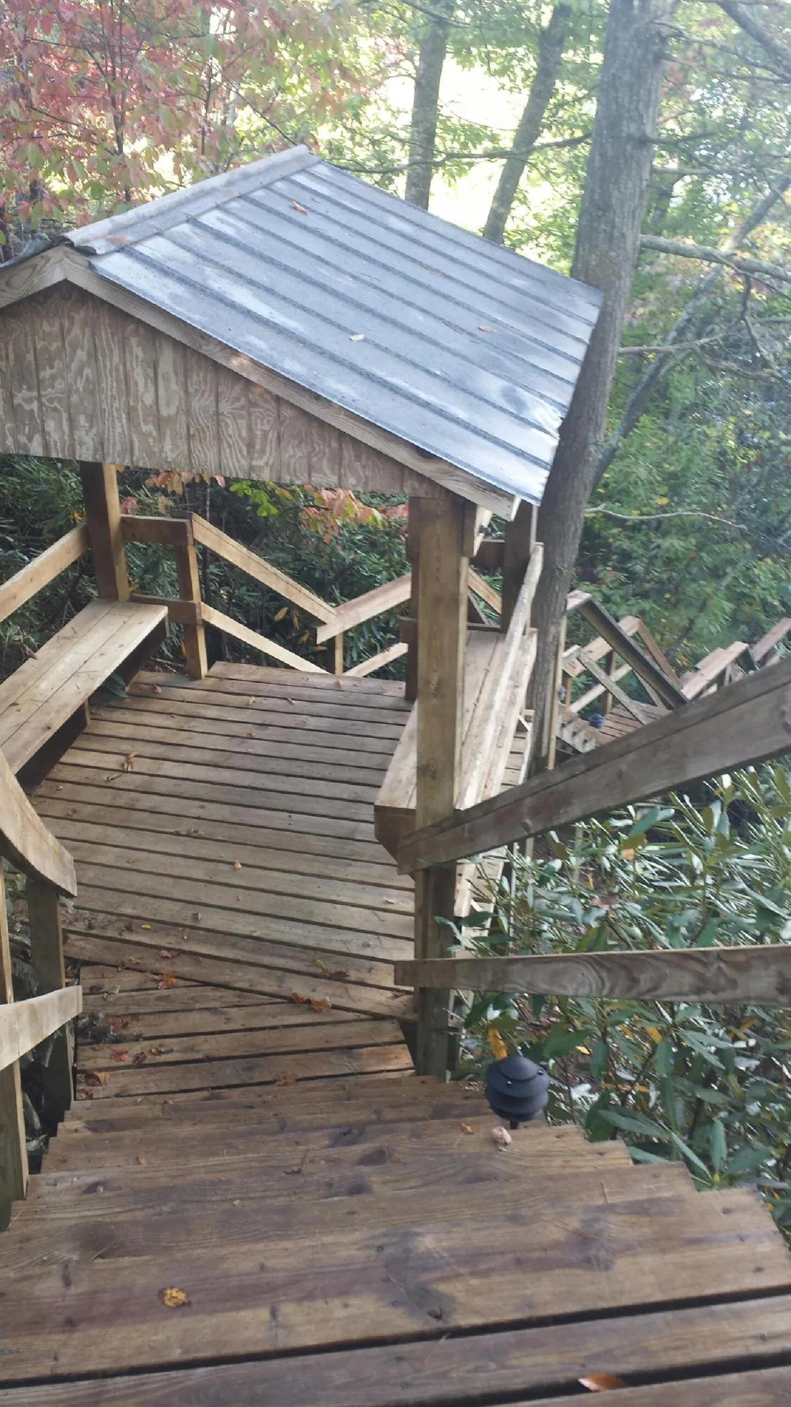Metal roofed shelter over wooden steps on a wooded walkway — Skylight Repair & Installation work by our crew in Poneto