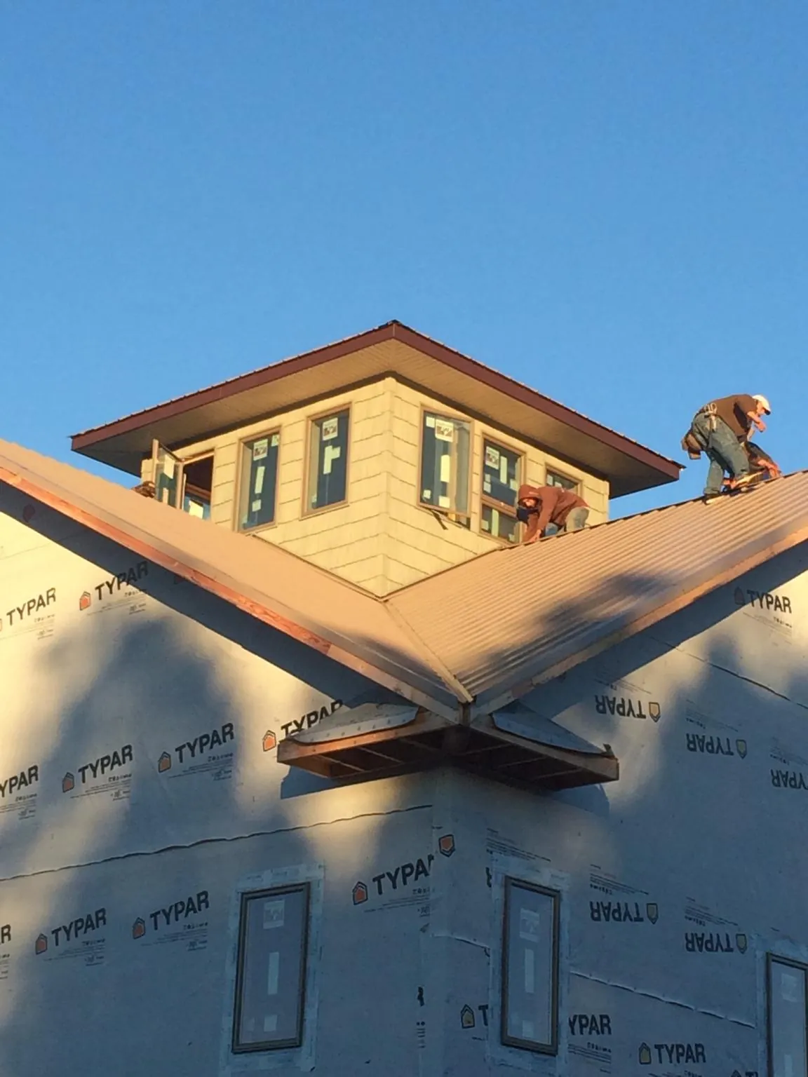 Roofers working around a rooftop cupola on a new metal roof at sunset — Roof Waterproofing in Poneto by Roofing Brothers